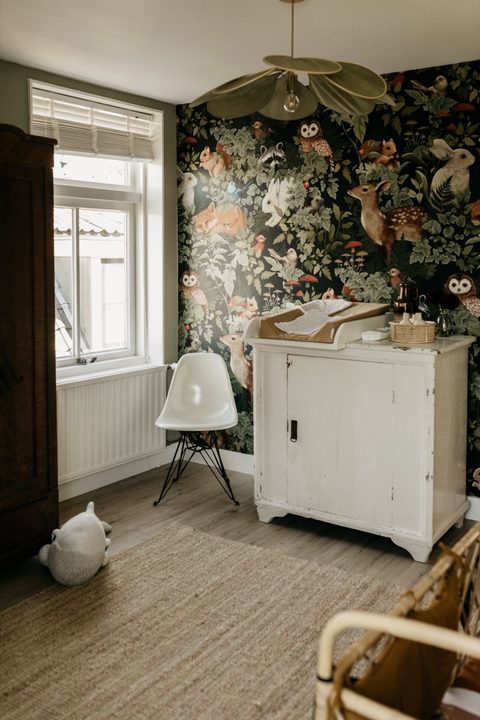 Babykamer met dierenbehang, een witte vintage commode, een witte Eames-stoel en een jute vloerkleed