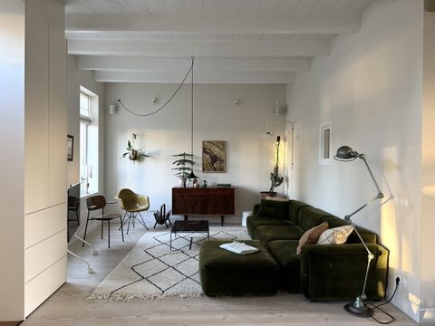 Woonkamer met groene velours bank, vintage dressoir en Berber vloerkleed
